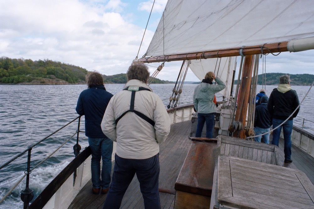 Passengers in casual clothes and jackets on the open deck of a wooden sailing ship on the Oslofjord, no text, no logos, no people