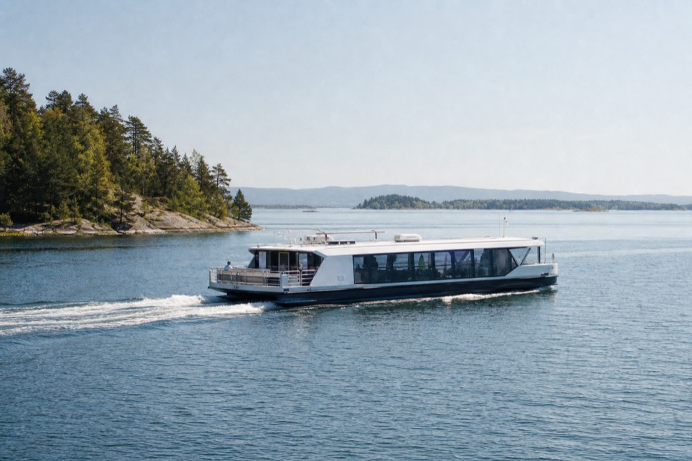 A silent electric boat gliding across calm Oslofjord water near forested islands, no text, no logos, no people.