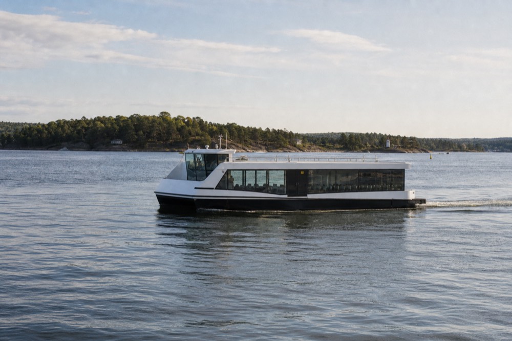 A silent electric cruise boat gliding across calm Oslofjord water near green islands, no text, no logos, no people